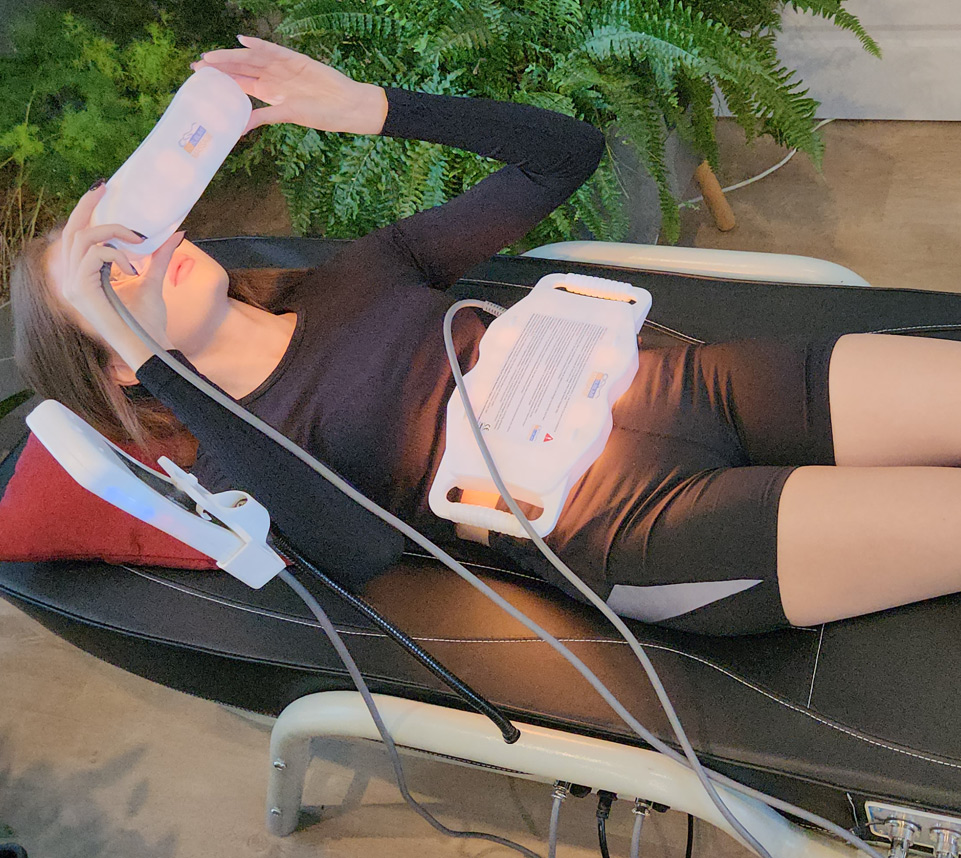 Woman relaxing beneath the jade thermal therapy heater of the SO Sublime massage bed